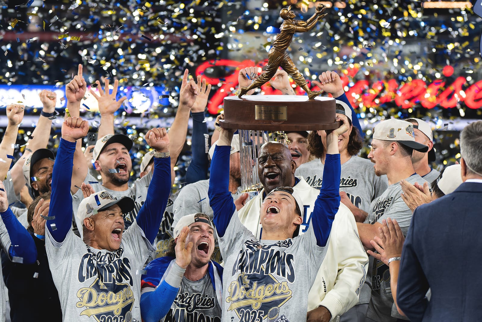 A team celebrating a World Series title, hoisting the trophy amid falling confetti.